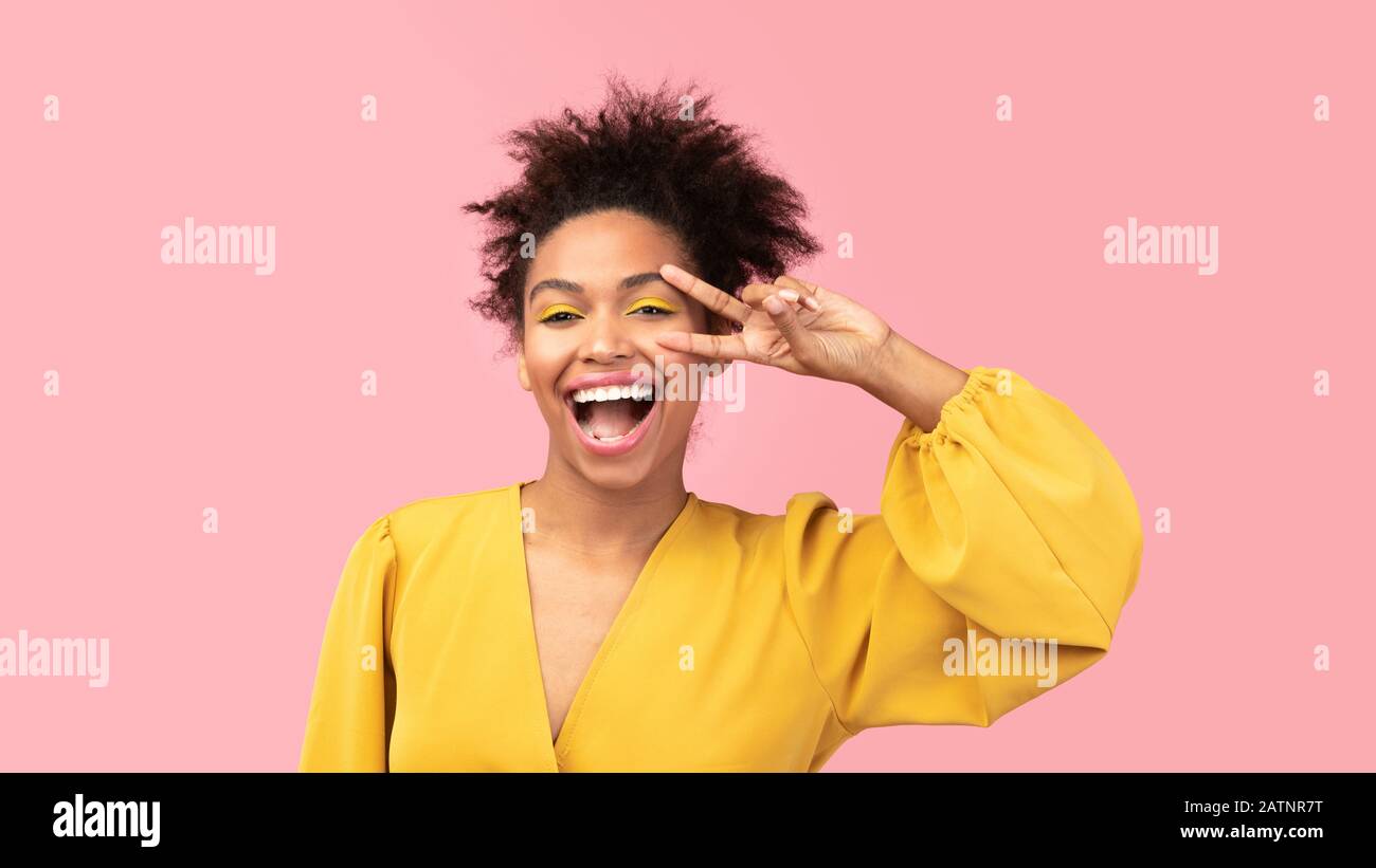 Fröhliches afro-Mädchen mit V-Zeichen und Blick auf die Kamera Stockfoto