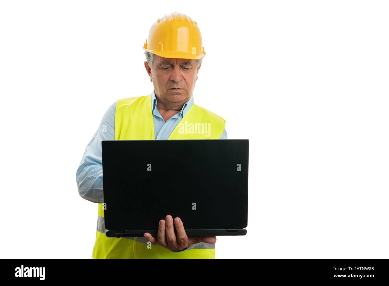 Alter Techniker mit ernsthaftem Ausdruck, der auf einem weißen Hintergrund einen PC oder Laptop betrachtet Stockfoto