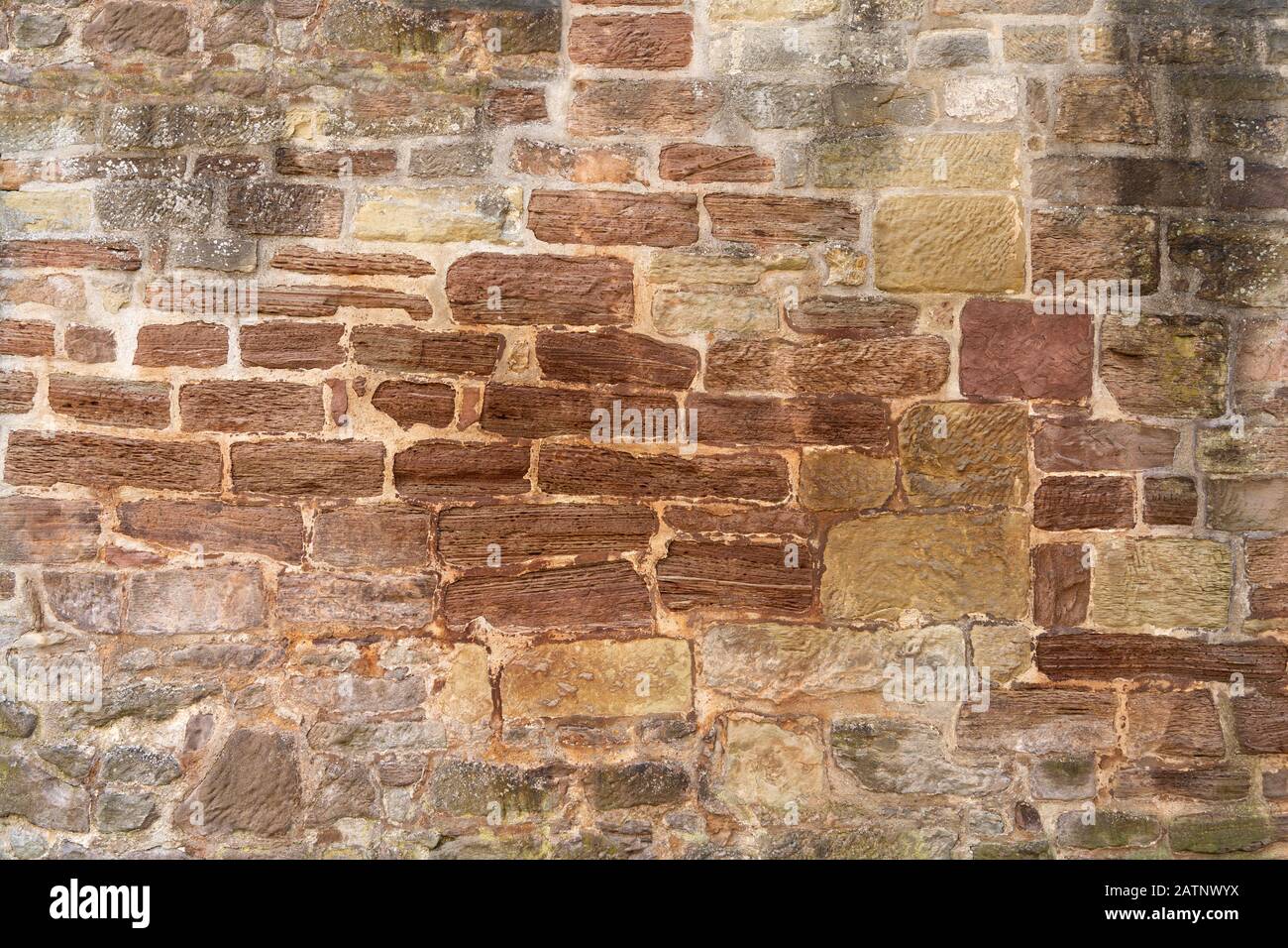 Sehr alte, braune, teils stark verwitterte Steinwand Stockfoto