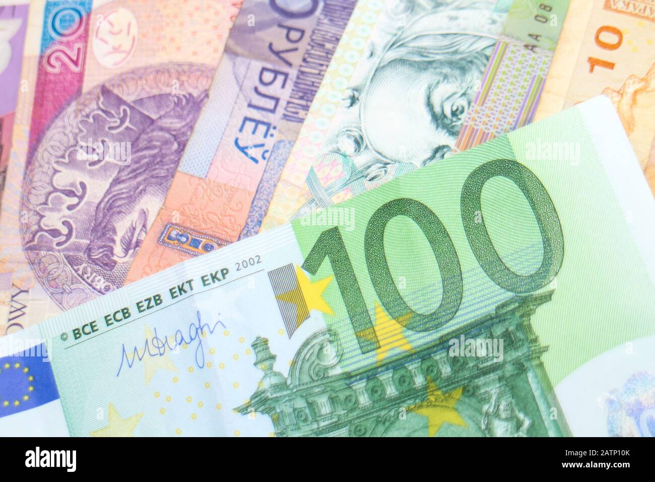 Eine 100-Euro-Banknote, die über einem Stapel von Regenbogenbanknoten verschiedener Weltwährungen angeordnet wurde, darunter Euro, Schekel, Rand und Polnisch Złoty. Stockfoto