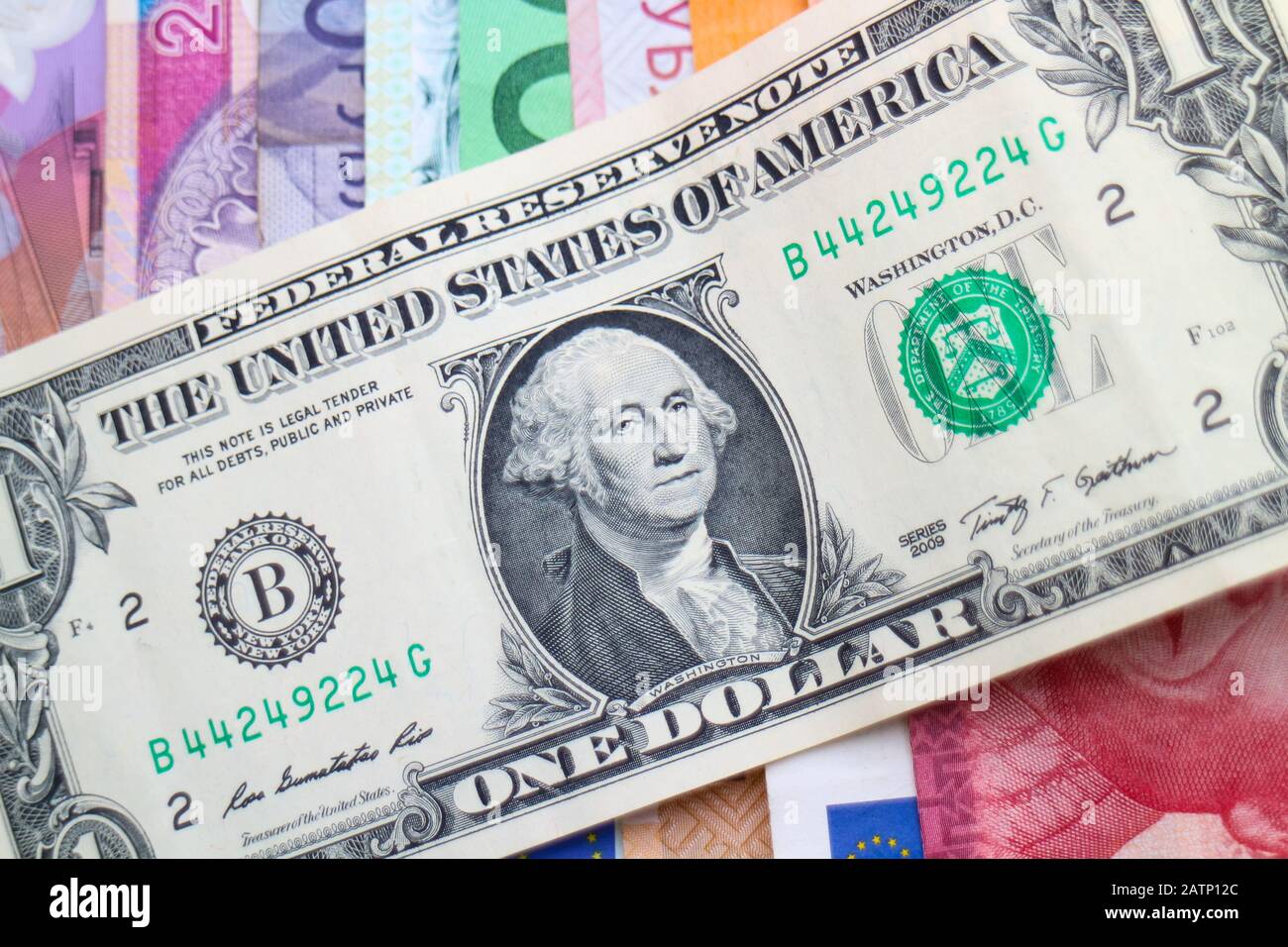 US-Dollar-Banknote diagonal auf einem Stapel von Regenbogenbanknoten verschiedener Weltwährungen, darunter Euro, Schekel, Rand und Polnisch Złoty. Stockfoto