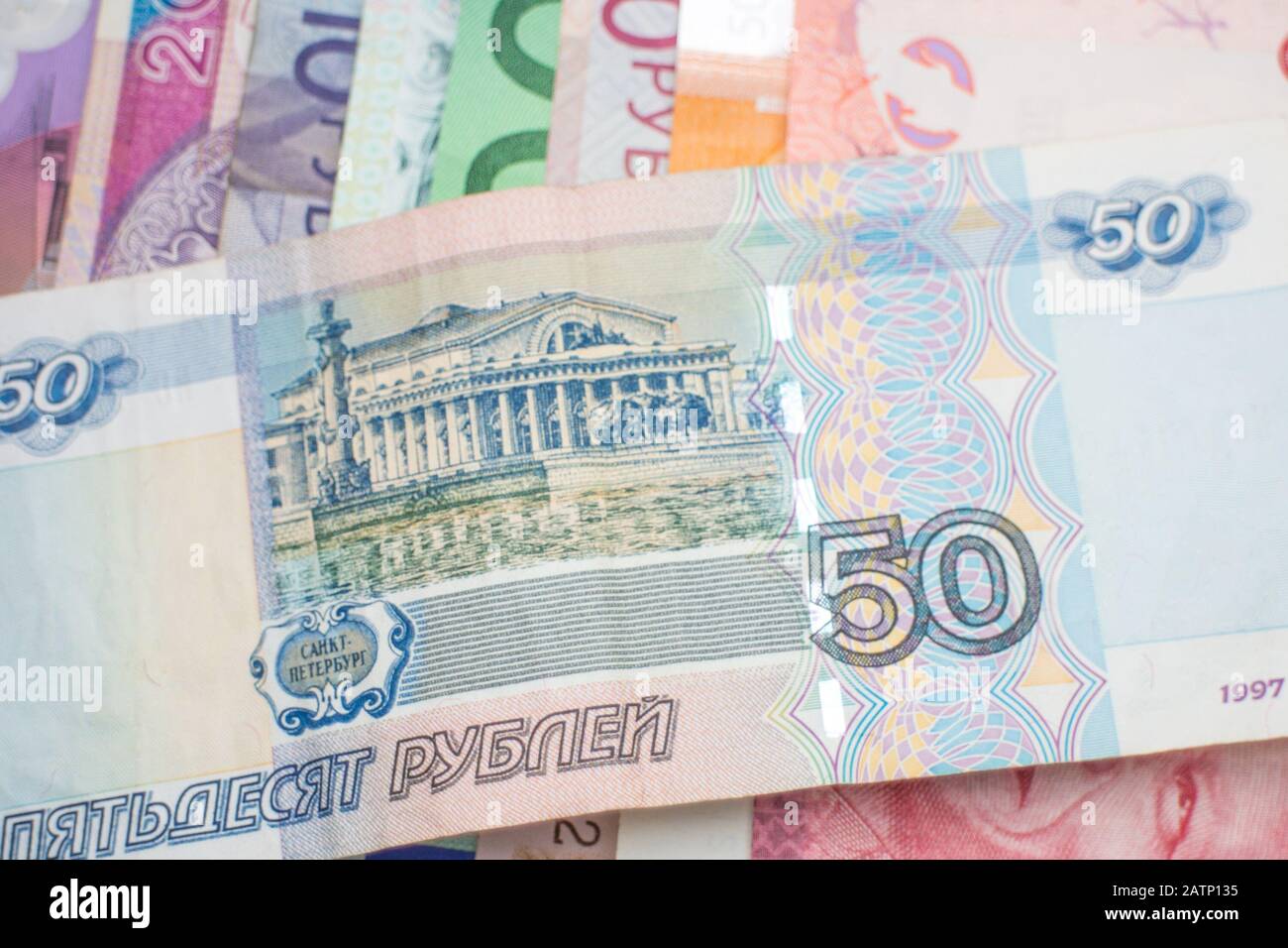 Eine russische Rubel-Banknote, die über einem Regenbogen von Banknoten verschiedener Weltwährungen angeordnet wurde, darunter Euro-Banknoten, australische Dollar und Schekel. Stockfoto