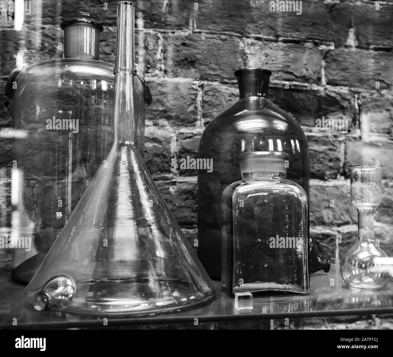 Vintage Chemical Ware ist auf Backstein-Wandhintergrund im Regal. Schwarzweißfoto Stockfoto