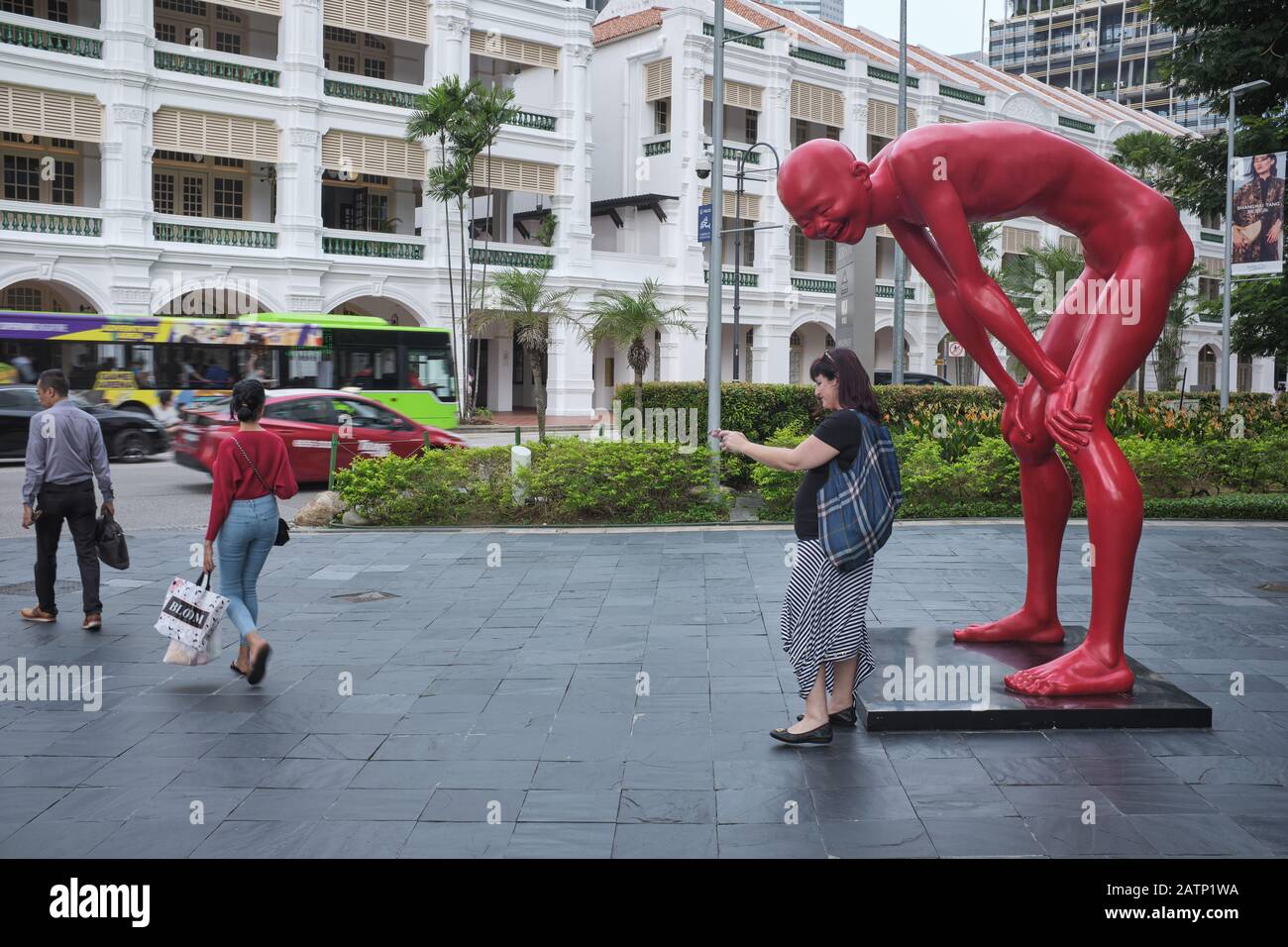 Ein Tourist nimmt ein selfie vor der Skulptur "Meile von Chen Wen Ling, in Raffles City, Singapur; b/g: Teilweiser Blick auf das Raffles Hotel Stockfoto