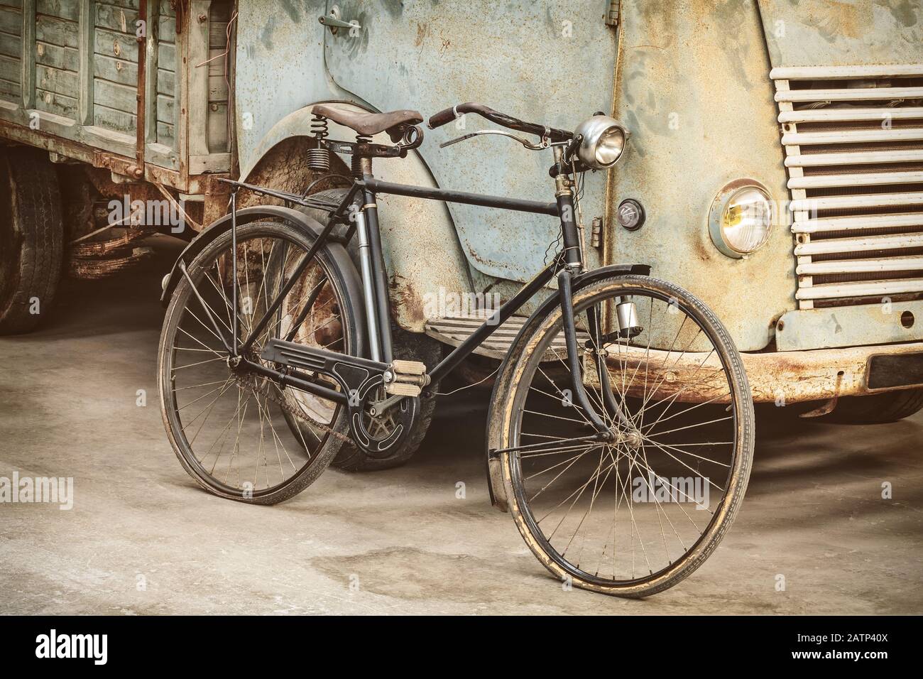 Das im Retro-Stil gestaltete Bild eines alten Fahrrads und eines rostigen Lastwagens in einer Scheune Stockfoto