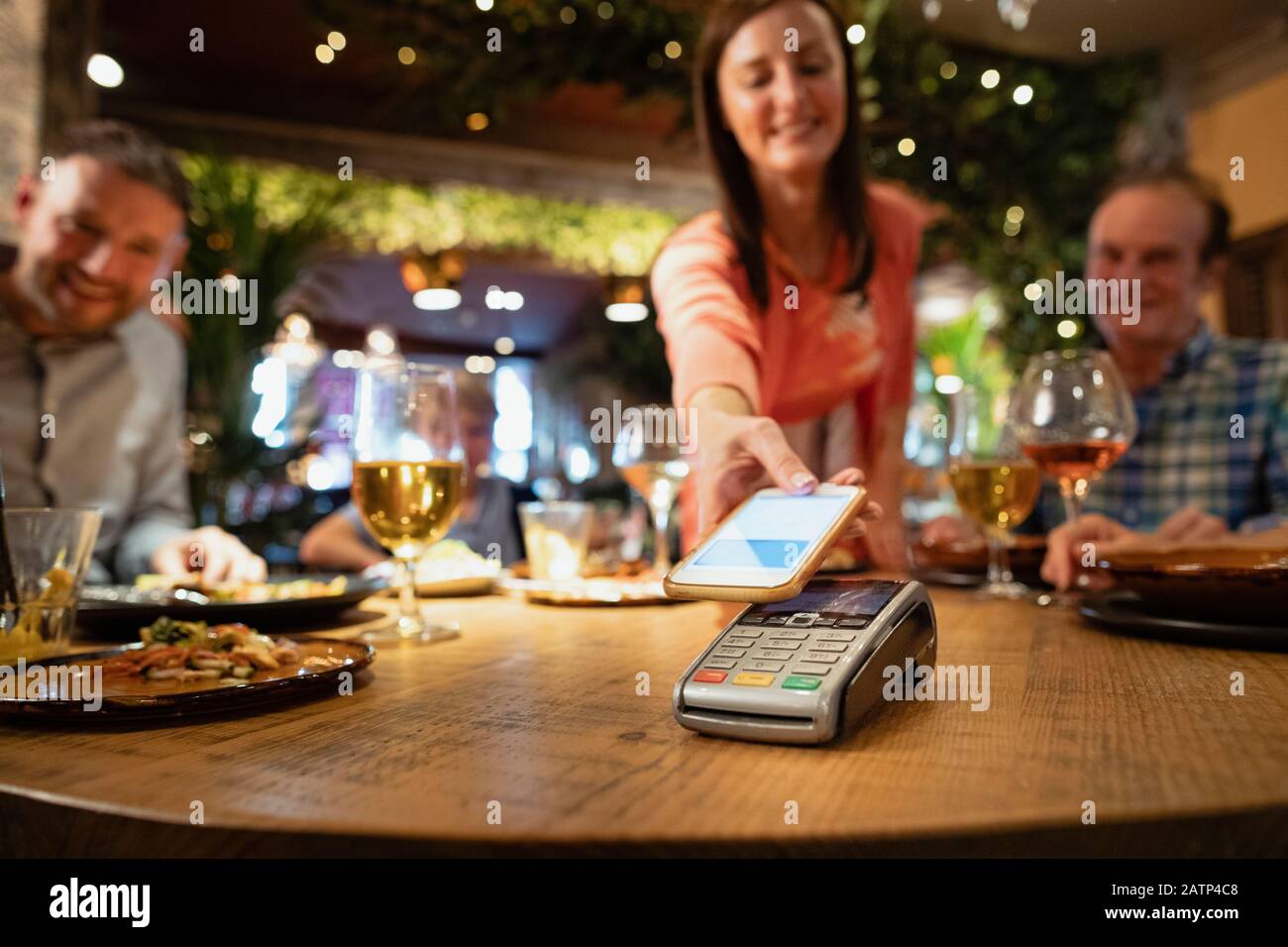 Eine Frau, die eine Mahlzeit mit kontaktloser Zahlung über ihr Telefon bezahlt. Stockfoto