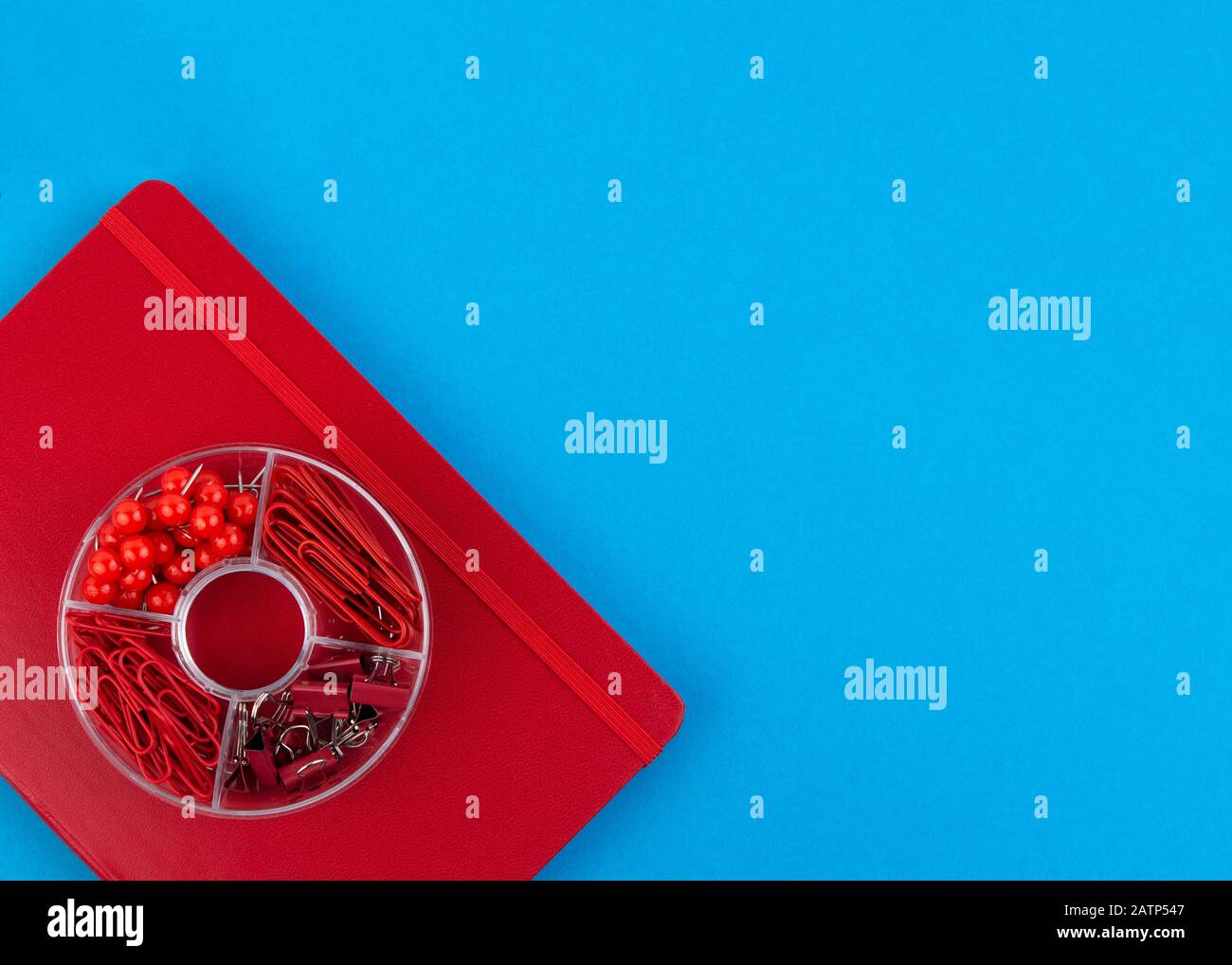 Red Business Notebook und Schreibwaren auf blauem Tisch. Zurück zur Schule oder zum Arbeitsplatz abstrakter Hintergrund. Minimale Zusammensetzung. Stockfoto