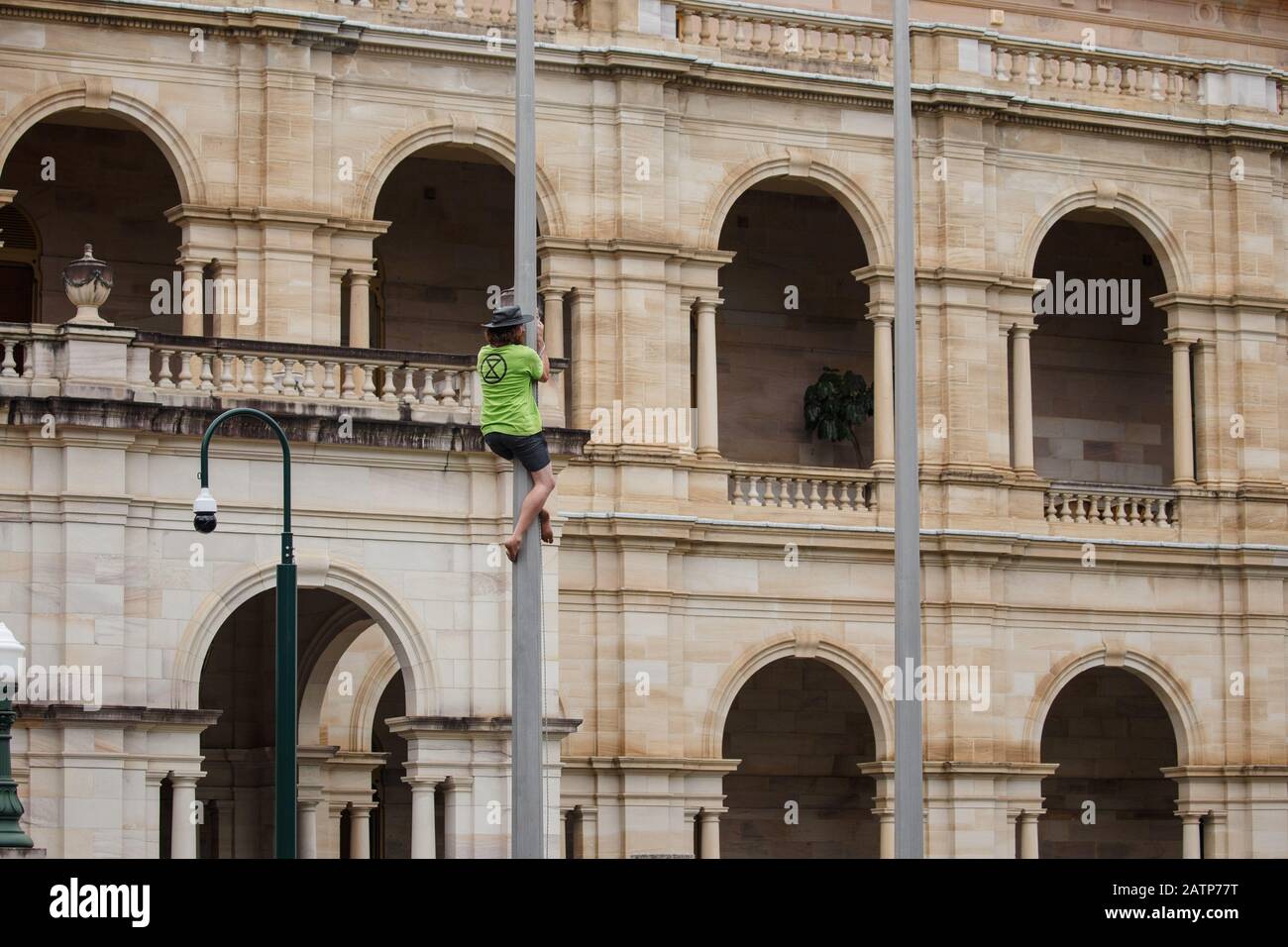 Während der Demonstration in Brisbane besteigt ein Protestler einen Fahnenmast.Extinction Rebellion Demonstranten gelobten, die Wiedereröffnung des Parlaments von Queensland außerhalb des Parliament House in Brisbane City zu stören, um ein Ende der Regierungskorruption zu fordern, Dringende Maßnahmen zum Klimawandel und für den Verzicht auf die Unterstützung der Adani-Kohlemine an der zentralen Küste von Queensland. Die international bekannte Gruppe hält das Geschäft wie gewohnt durch die Blockierung von Straßen, die Organisation von Kundgebungen und die Störung der Minengeschäfte im Bemühen, politische Veränderungen zu erzwingen, ein. Stockfoto