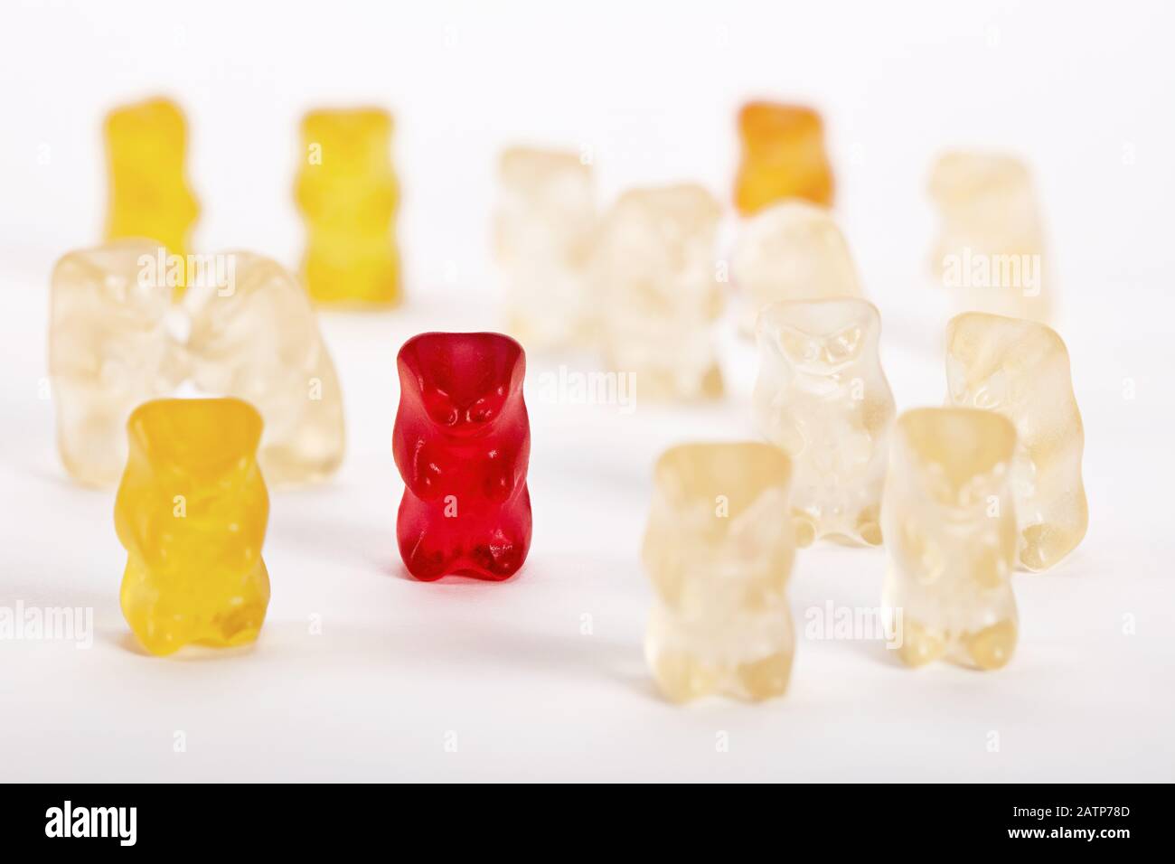 Gruppe von Gummibären, bei denen ein Bär ausgeschlossen ist. Sozialer Ausschluss, Diskriminierung oder Einsamkeitsbegriff. Stockfoto