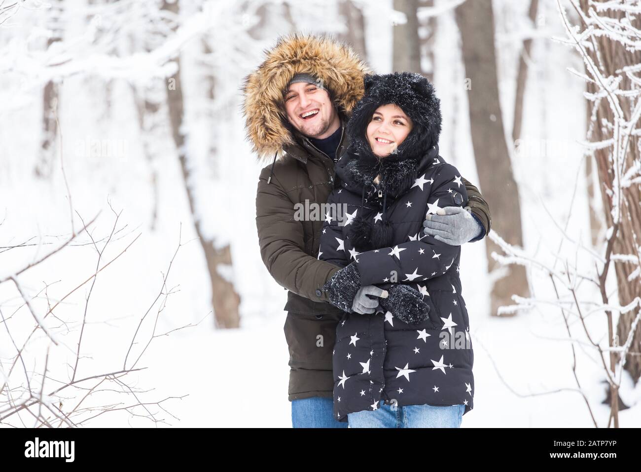 Junge Paare, die in einem verschneiten Park spazieren gehen. Wintersaison Stockfoto