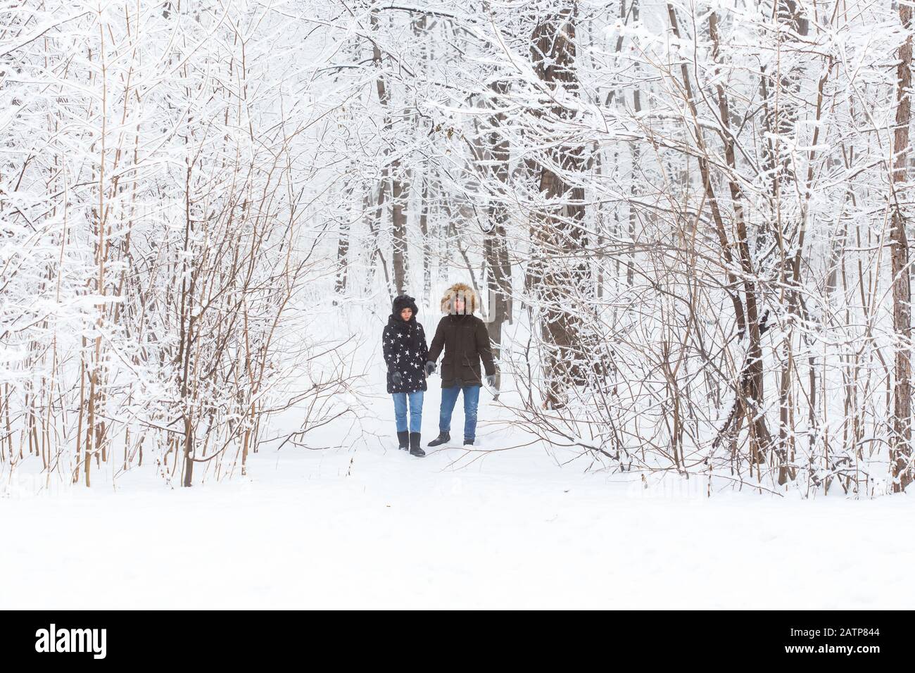 Junge Paare, die in einem verschneiten Park spazieren gehen. Wintersaison Stockfoto