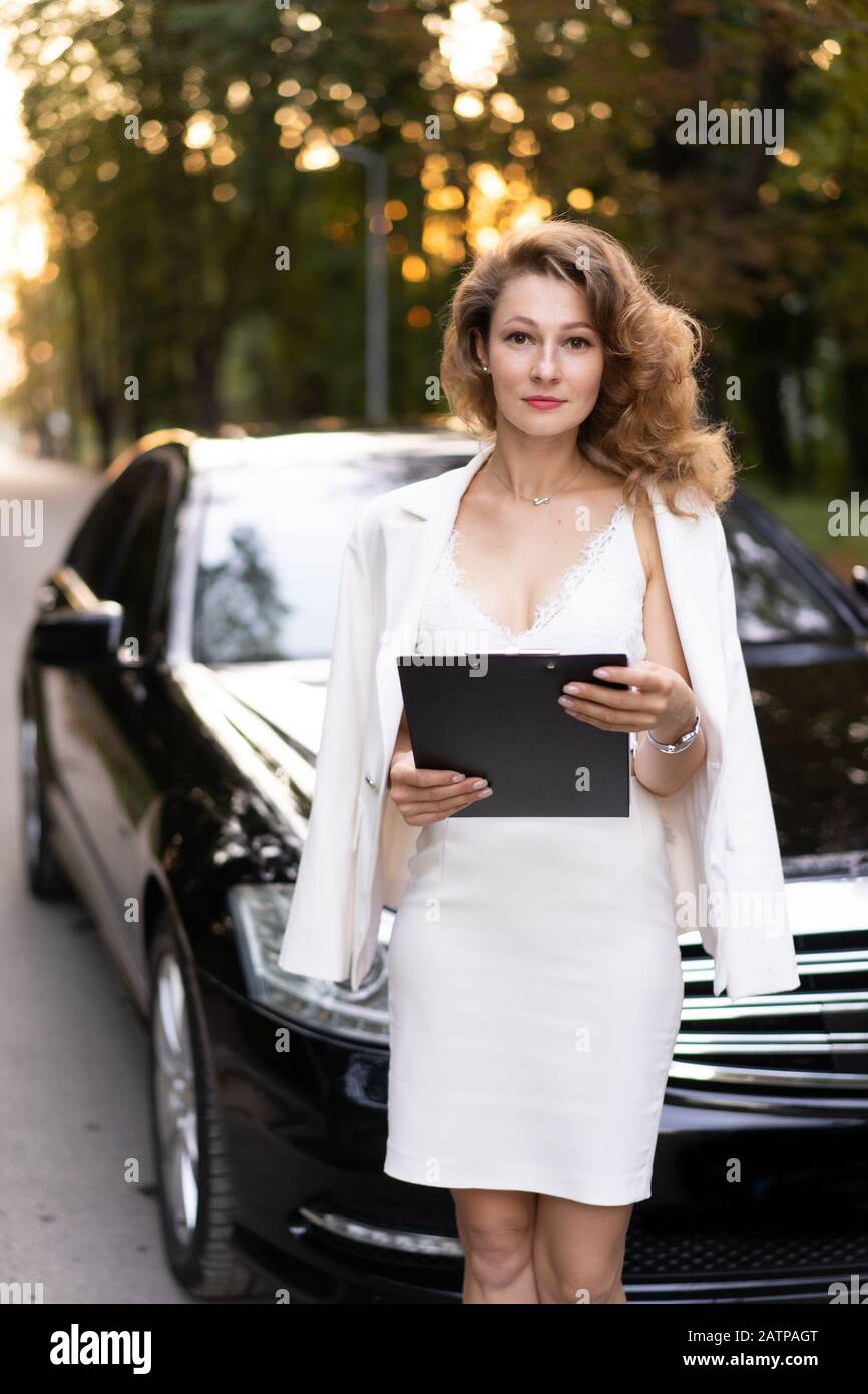 Vorderansicht der schönen Geschäftsfrau mit Zwischenablage in der Nähe des Autos. Stockfoto