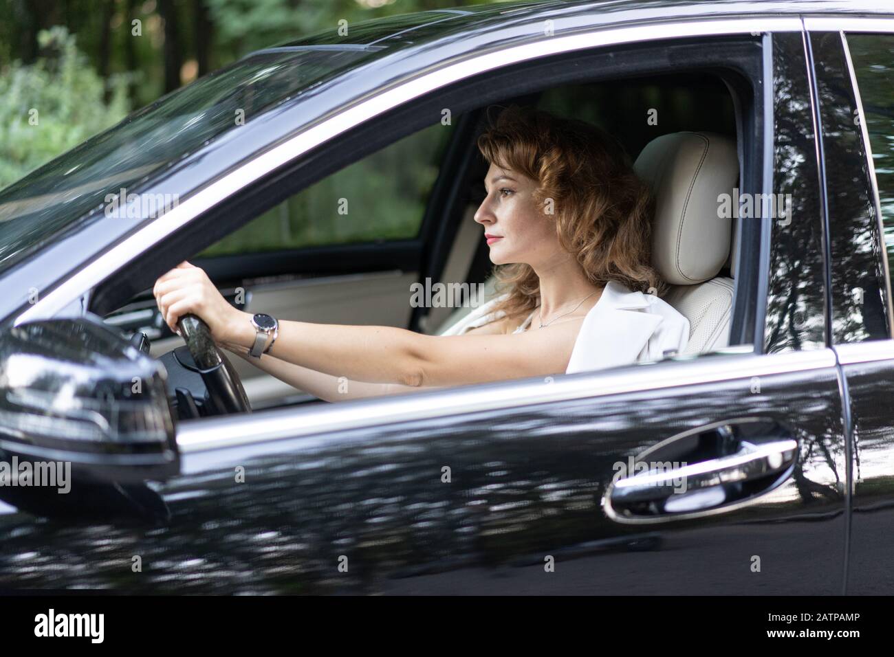 Selbstbewusste schöne Frau mit Armbanduhr, die Auto fährt. Stockfoto