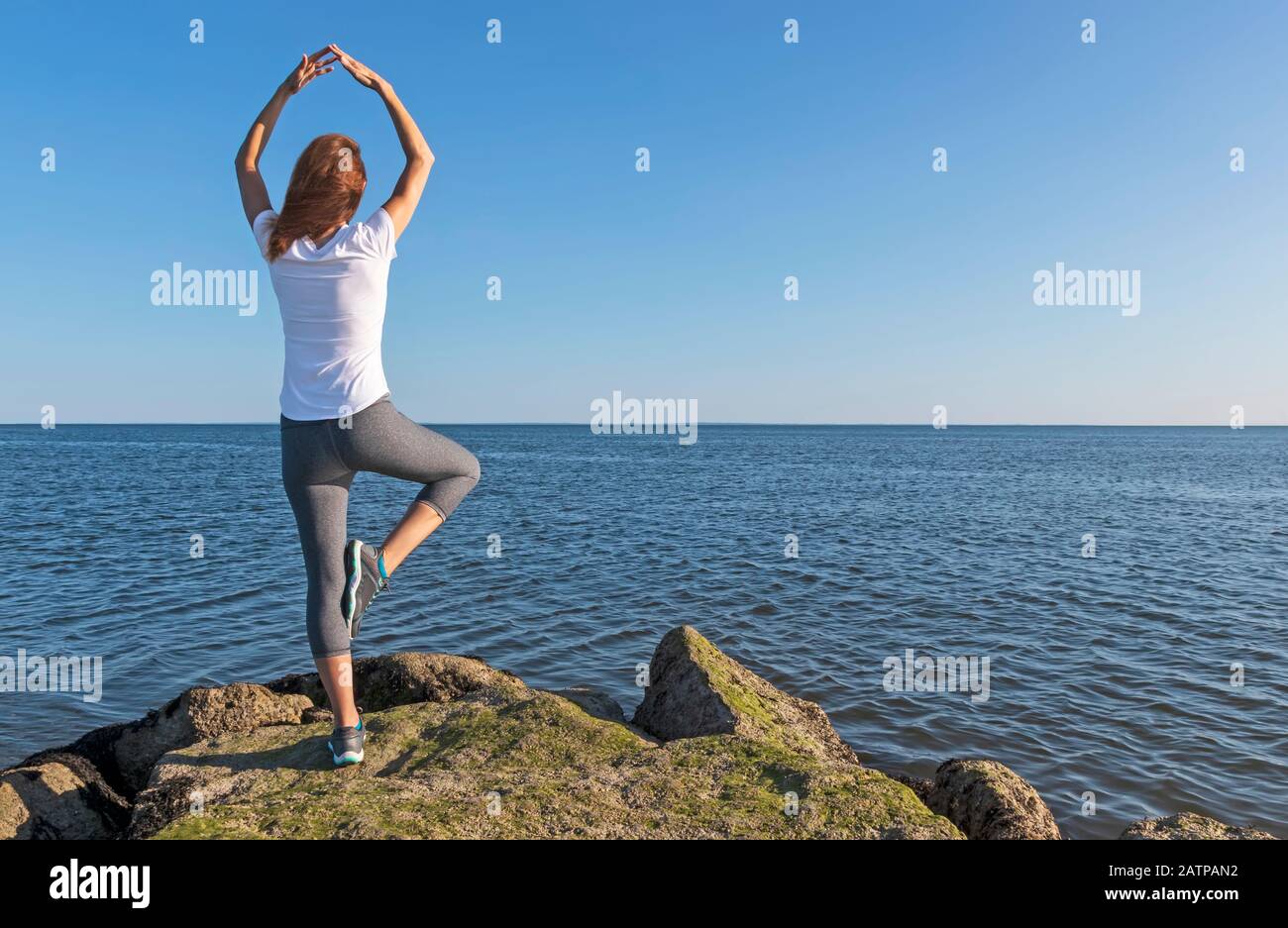 Woman Yoga-Pose mit Blick auf den Ozean Stockfoto