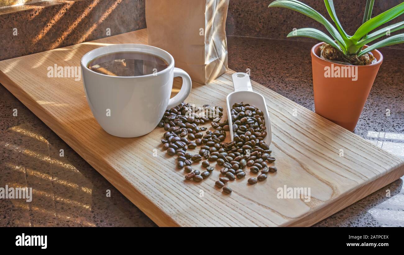 Frisch gebrühter Kaffee mit Kaffeebohnen und Holzschneidebrett. Küche Innenbereich. Stockfoto