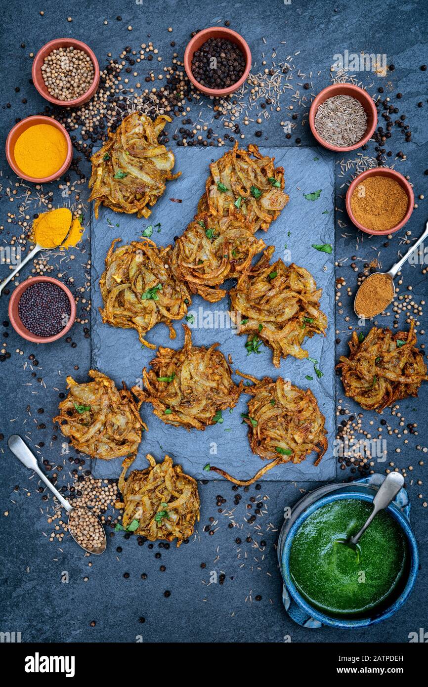 Hausgemachte Zwiebel-Bhajis mit Gewürzen auf Schiefergrund Stockfoto