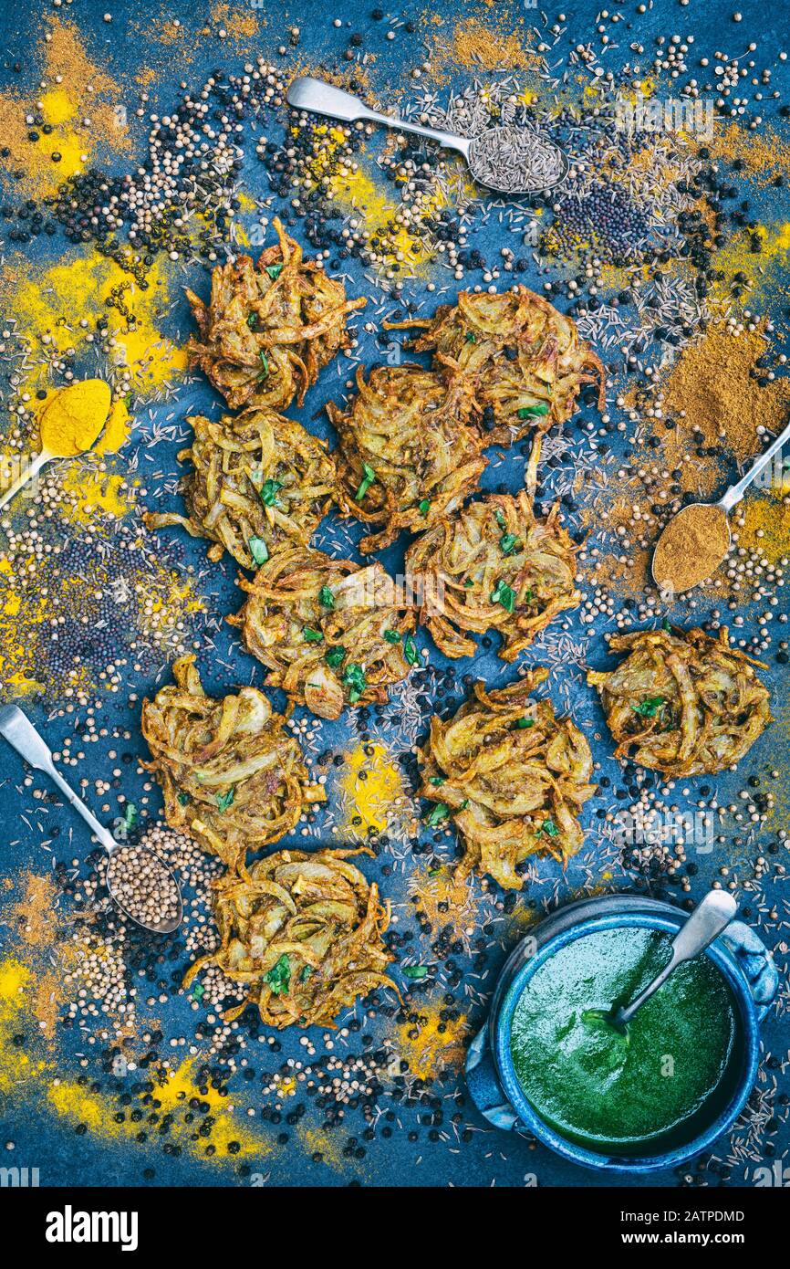 Hausgemachte Zwiebel-Bhajis mit Gewürzen auf Schiefergrund Stockfoto