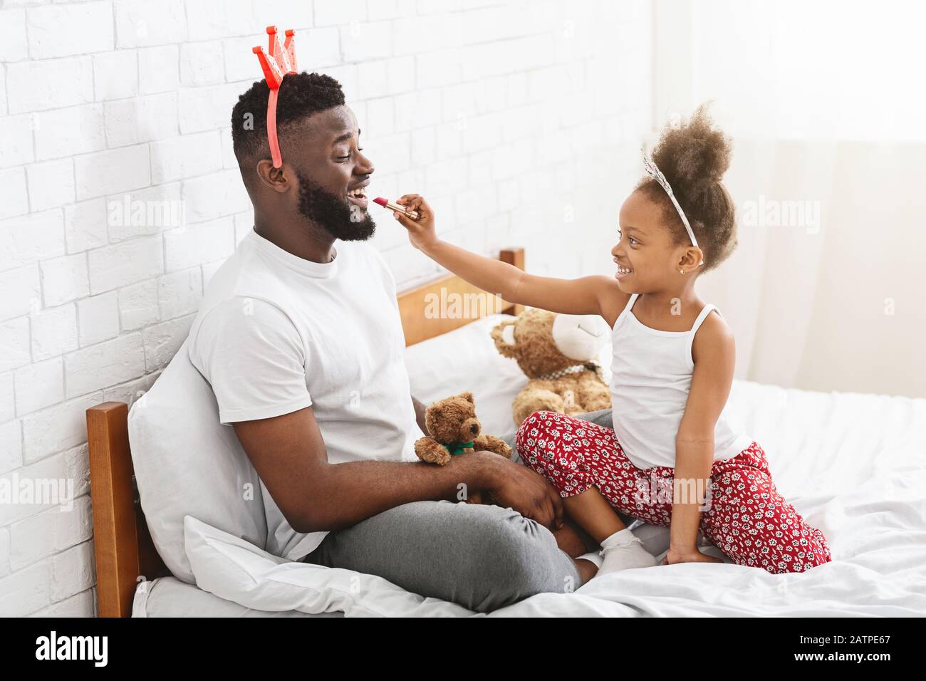 Schwarzes kleines Mädchen, das Lippenstift auf ihre Papa Lippen legt Stockfoto