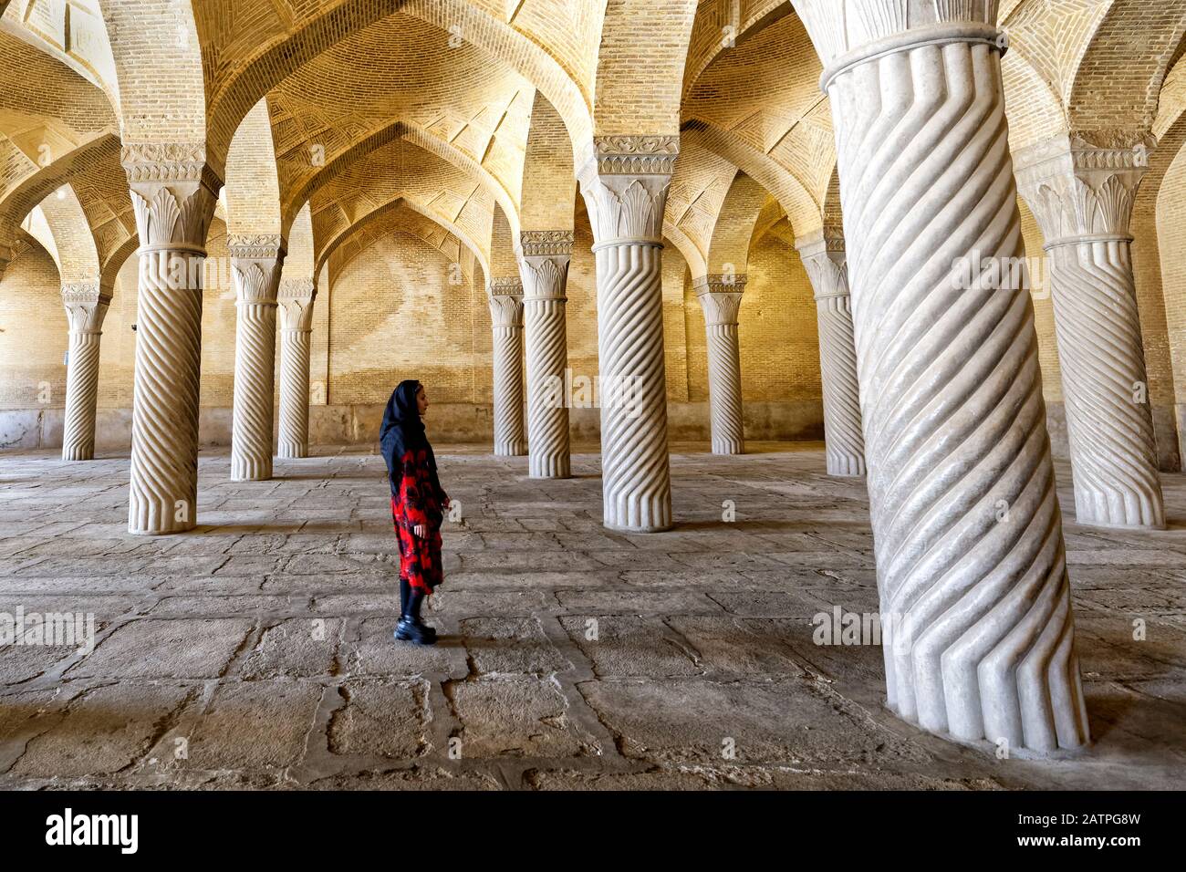 Iranerin, die mit Schabestan-Säulen, Vakil-Moschee, Shiraz, Fars Provinz, Iran durch den Betsaal spazieren geht Stockfoto