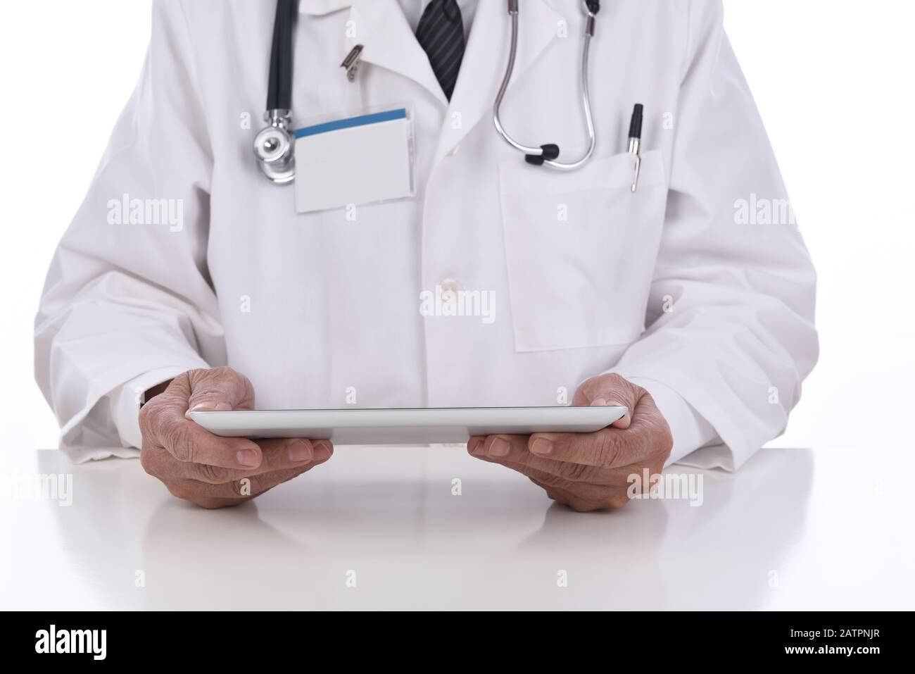 Nahaufnahme eines Arztes, der einen Tablet-Computer in den Händen hält, während er an seinem Schreibtisch sitzt. Der Schwerpunkt liegt auf Tablet Stockfoto