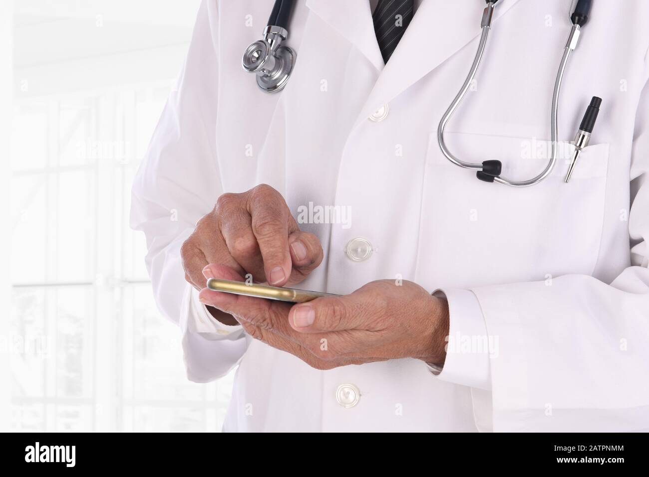Nahaufnahme eines Arztes, der auf seinem Handy in einer modernen medizinischen Einrichtung getextet wird. Der Mensch ist nicht erkennbar. Stockfoto