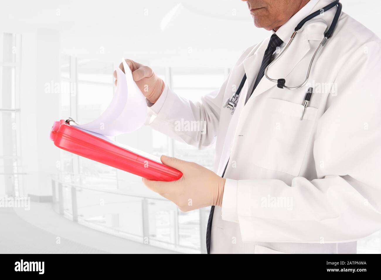Nahaufnahme eines Arztes, der in einer modernen medizinischen Einrichtung steht. Der Mann hält einen Patienten in der Krankengeschichte und hält ein Diagramm in seinen Händen. Stockfoto