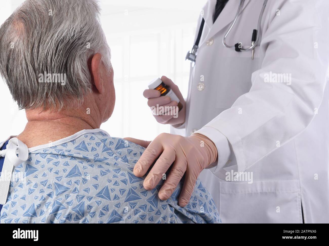 Die Nahaufnahme eines älteren männlichen Patienten, der als Arzt einen Krankenhauskeimen trägt, legt seine Hand auf die Schulter und bietet Komfort. Stockfoto
