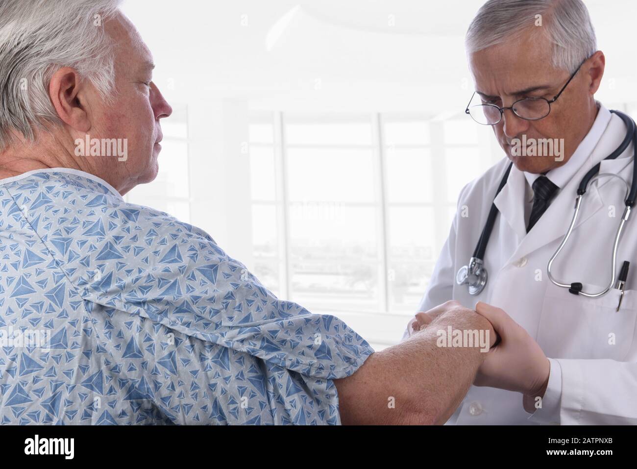 Nahaufnahme eines älteren männlichen Patienten, der einen Krankenhauskeimen trägt, während ein Arzt seinen rechten Arm untersucht. Der Fokus liegt auf dem Patienten. Stockfoto