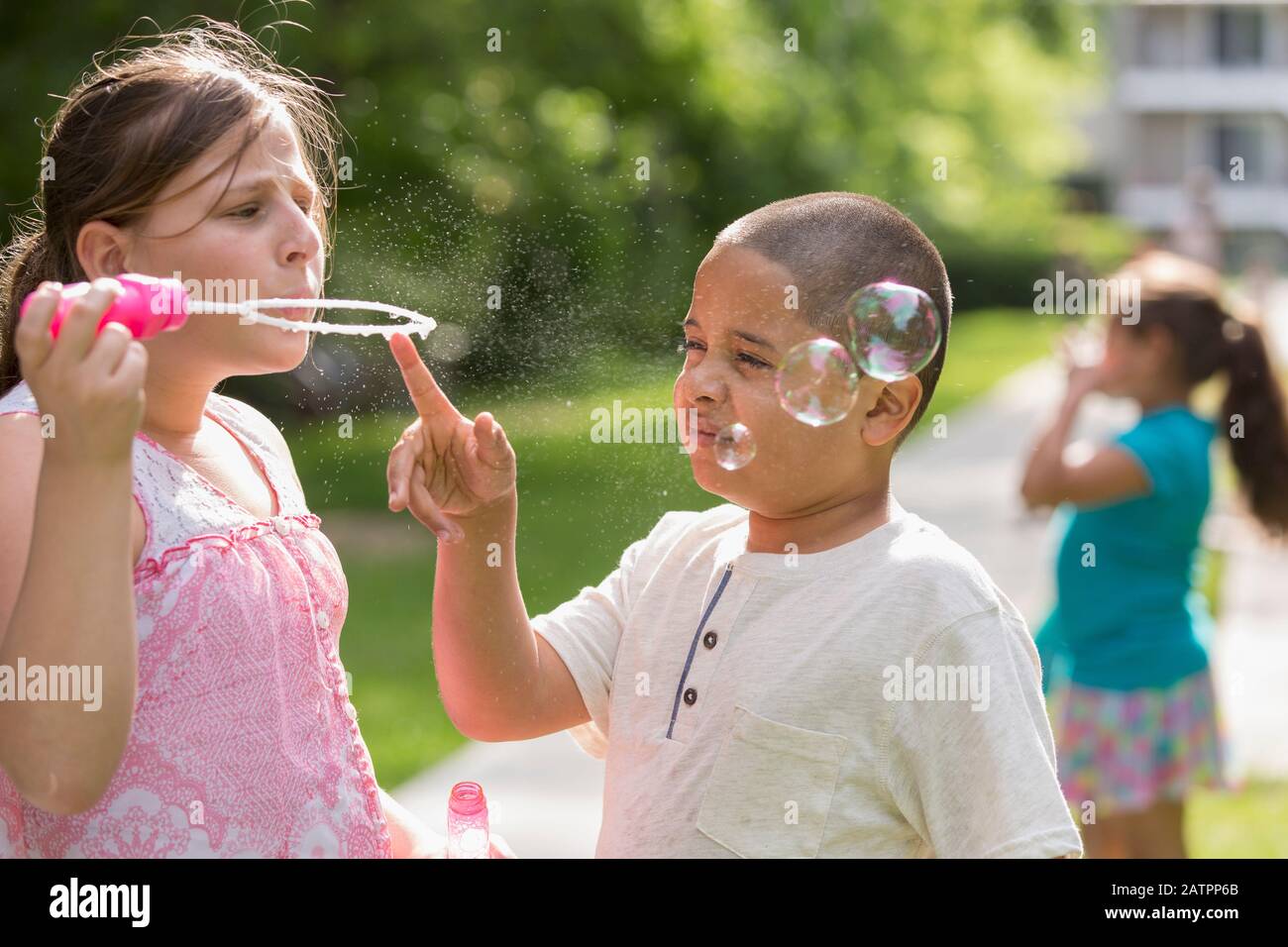 Ein Mädchen steht blasen Blasen mit einem Jungen berühren die Seifenblasenstab Stockfoto
