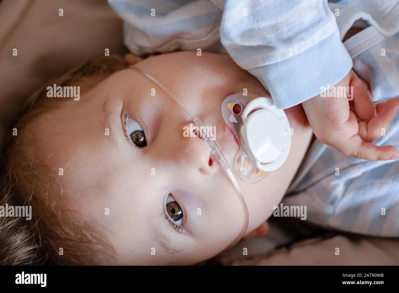Baby Junge mit zerebraler Pläse erhält Sauerstoff über Nasenprongs, um die Sauerstoffsättigung zu gewährleisten. Nasenkatheter bei einem Patienten im Krankenhaus. Stockfoto