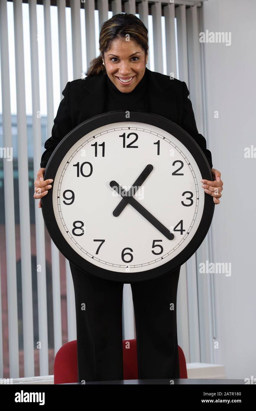 Porträt einer Geschäftsfrau mit Wanduhr. Stockfoto