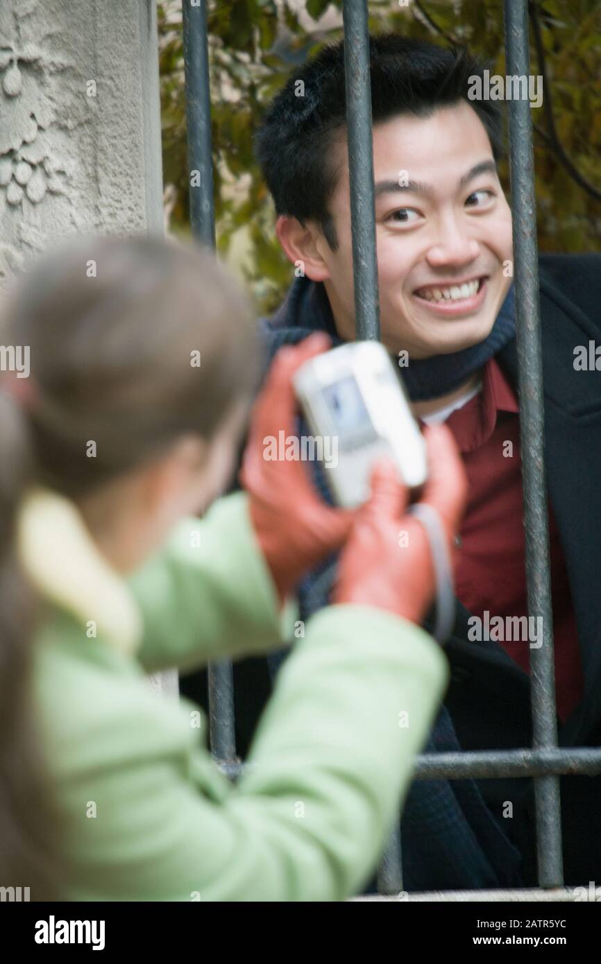 Rückansicht einer jungen Frau, die ein Bild von Ihre Freundin hinter einer Sicherheitsstange Stockfoto