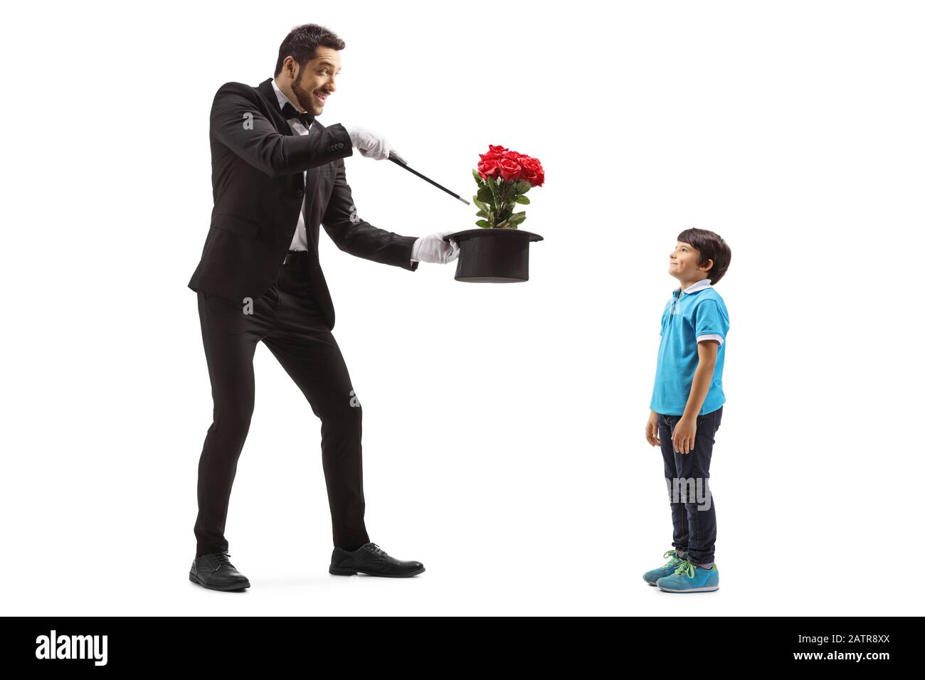 Lange Schuss eines Zauberers, der einen Hattrick mit Blumen vor einem Jungen macht, der auf weißem Hintergrund isoliert ist Stockfoto