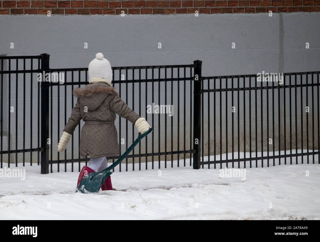 15. Januar 2020 - Montreal, Quebec, Kanada: Junges Mädchen, das im Winter auf einem Gehweg im Schnee mit einer Schaufel entlang eines Gebäudes spazieren ging, Rosemont Borough Stockfoto