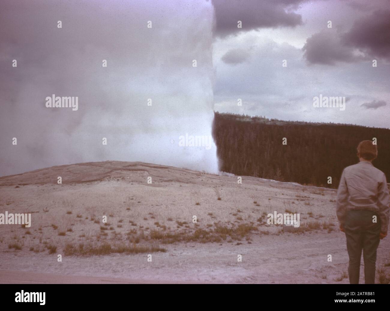 Nakuläres Foto, aufgenommen auf einer analogen 35-mm-Filmtransparenz, vermutet, dass es Touristen mit Geysir, 1965, abbildet. Zu den wichtigsten Themen/Objekten gehören Himmel, Geysir, Landschaft und Natur. () Stockfoto