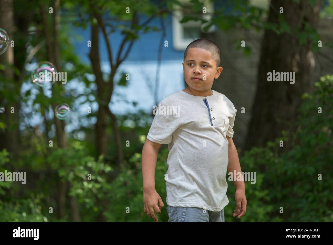 Pre-teen Junge draußen mit Bäumen im Hintergrund Stockfoto