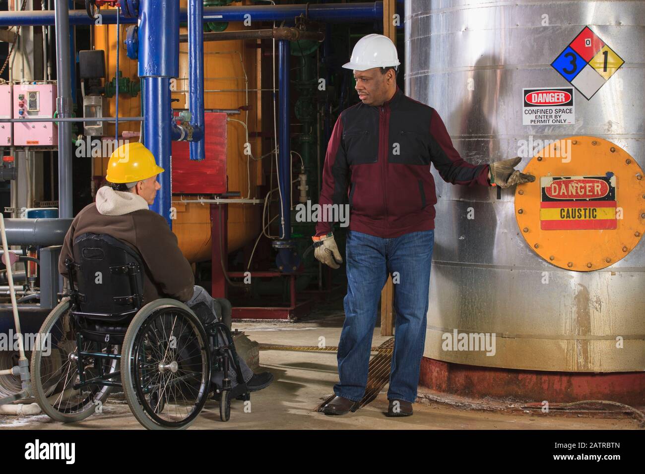 Behinderter Arbeitnehmer und ein Mitarbeiter, der an einem Industriearbeitsplatz arbeitet Stockfoto