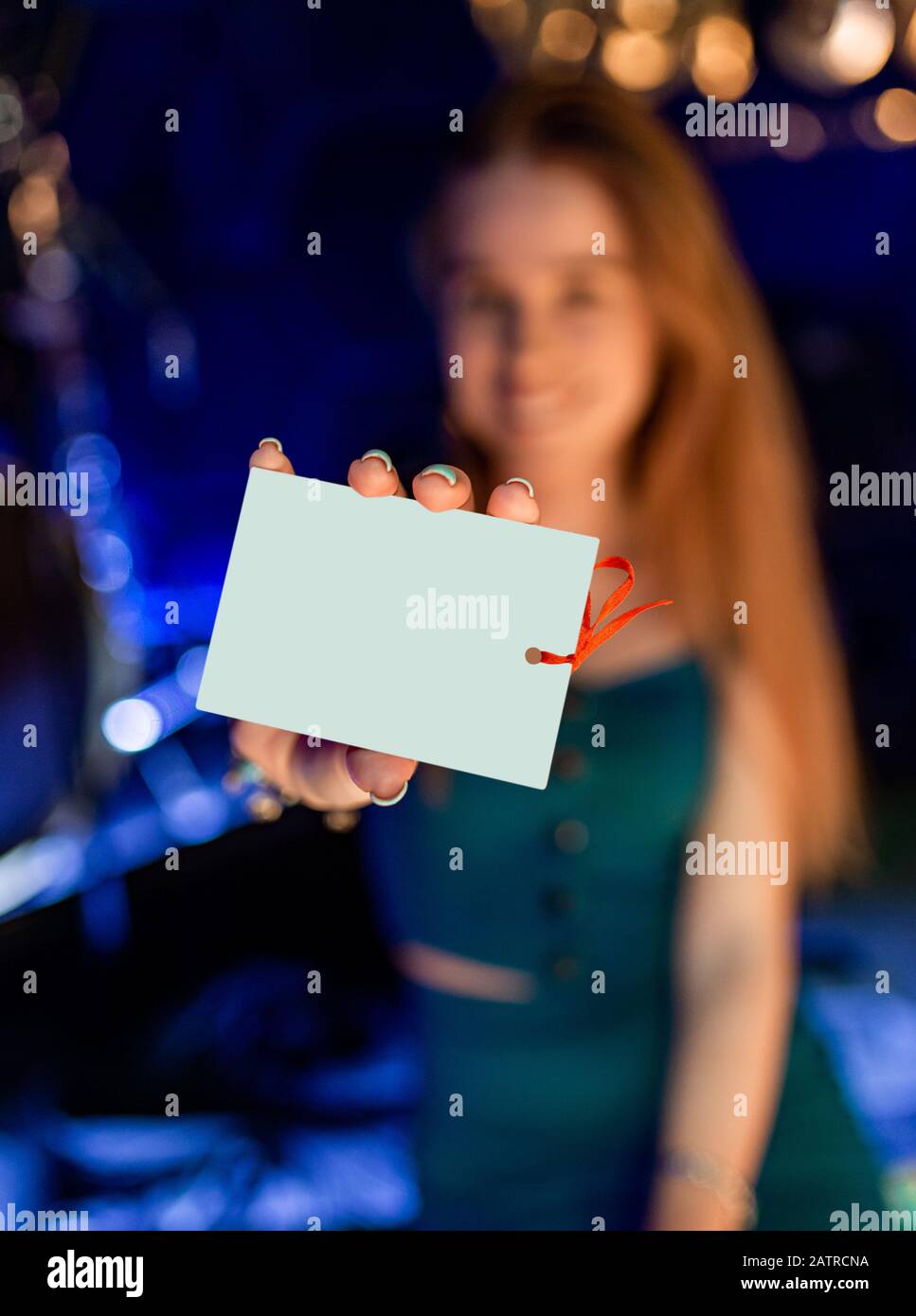 Geschenkgutschein. Aufgeregte Frau, die ein leeres Kartenschild mit Platz zum Kopieren von Text zeigt. Isoliert auf unscharfem Hintergrund Stockfoto