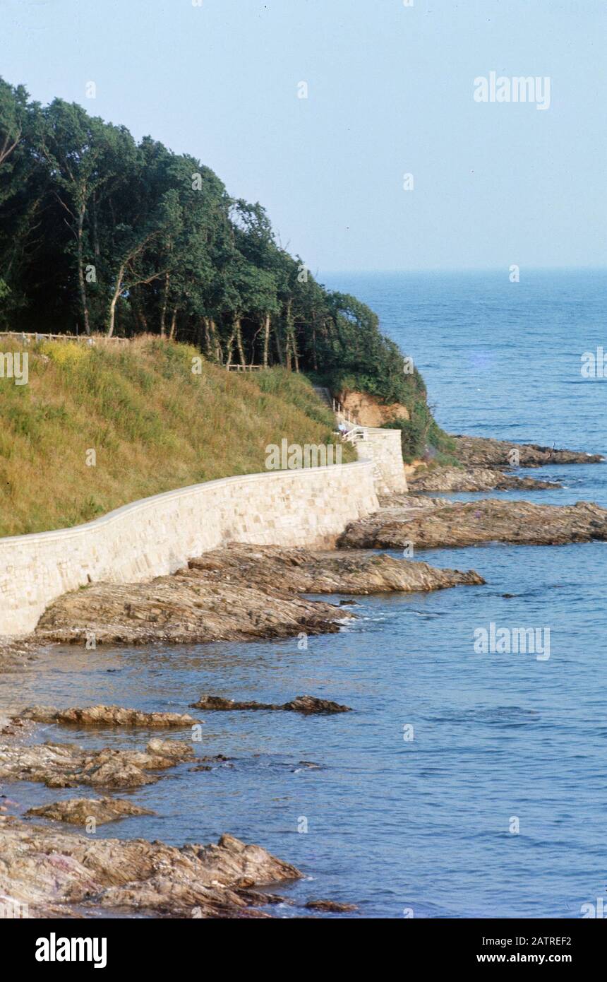Nakuläres Foto, aufgenommen auf einer analogen 35-mm-Filmtransparenz, mit der während des Tages, 1970, grünes Gras und Bäume neben dem Körper des Wassers dargestellt werden. Zu den wichtigsten Themen/Objekten gehören Shore, Sea, Water, Ocean, Beach, Rock, Vacation und Wave. () Stockfoto