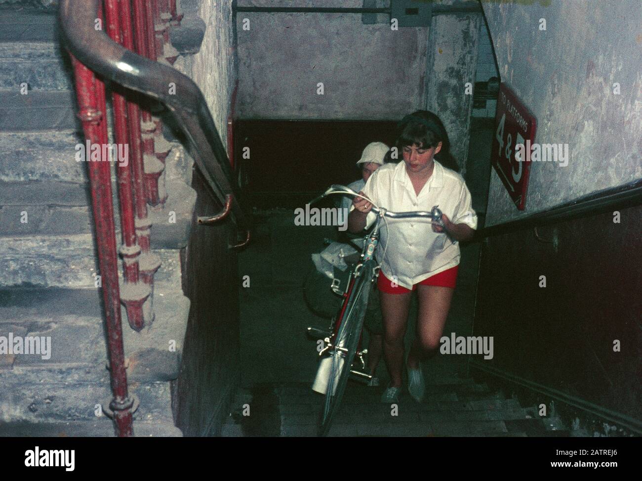 Ein Bild der Umgangssprache, das auf einer analogen 35-mm-Filmtransparenz aufgenommen wurde, war der Ansicht, dass Menschen, die Fahrräder über einen Treppenflug befördern, 1970, dargestellt werden. () Stockfoto