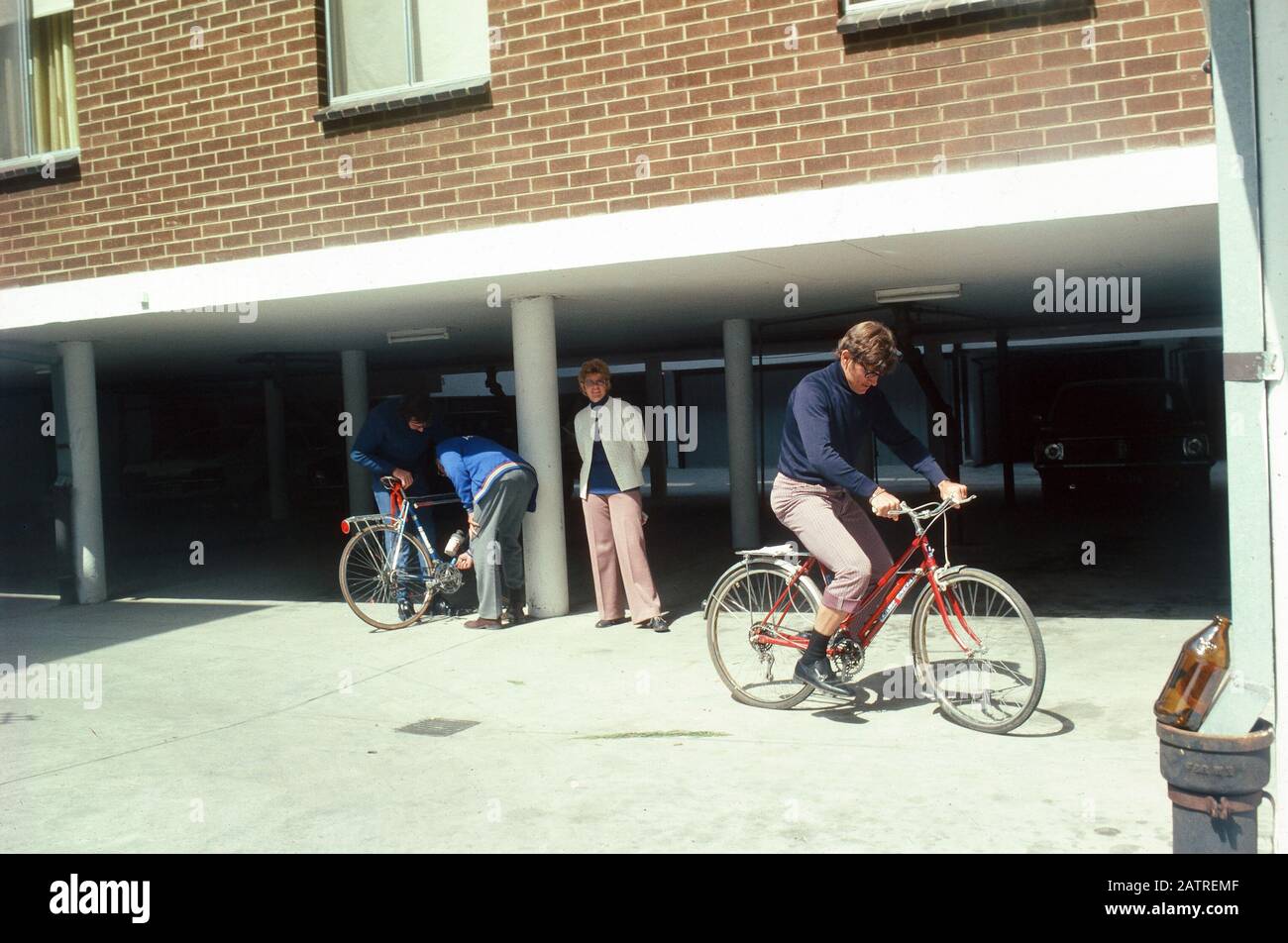 Nakuläres Foto, aufgenommen auf einer analogen 35-mm-Filmtransparenz, glaubte, den Mann in schwarzem Hemd und blauer Denimjeans mit rotem Fahrrad, 1970, darzustellen. Zu den Hauptthemen/Objekten, die erkannt wurden, gehört Das Fahrzeug. () Stockfoto