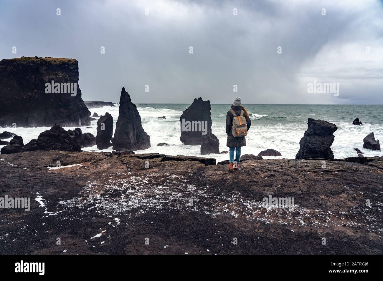 Frau, die auf der Klippe steht und die Macht des Ozeans auf dem Seeast reykjanesviti in Island beobachtet Stockfoto