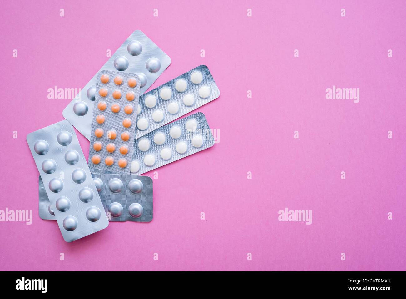 Verschiedene Medikamente - Aluminium-Blister-Tabletten mit Vitaminen, Tabletten, Kapseln auf pinkfarbenem Hintergrund. Pharmazeutisches Antibiotikum, Medikament. Pharma Stockfoto