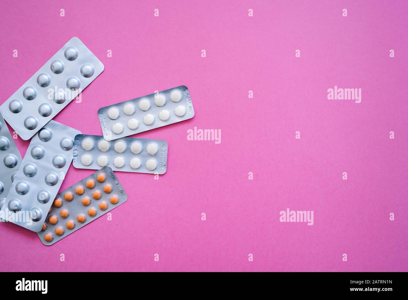 Verschiedene Medikamente - Aluminium-Blister-Tabletten mit Vitaminen, Tabletten, Kapseln auf pinkfarbenem Hintergrund. Pharmazeutisches Antibiotikum, Medikament. Pharma Stockfoto