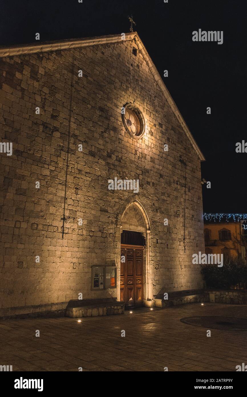 Eine nachts mit warmem Licht beleuchtete, mittelalterliche Steinkirche in einem alten französischen Dorf (10. Januar 2020) Stockfoto