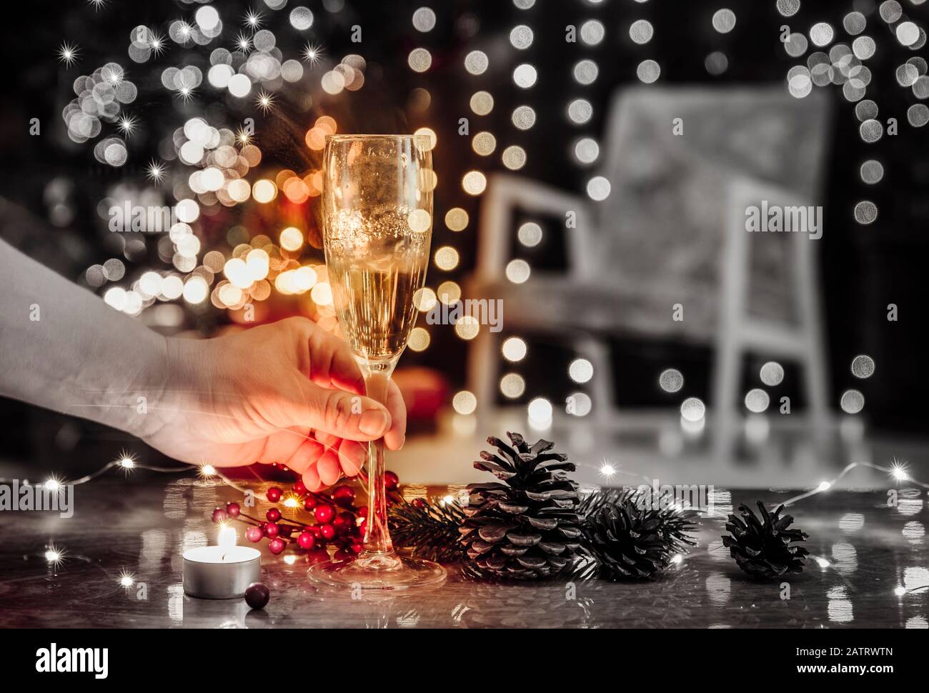 Weihnachtsfeiertage allein verbringen und Champagner allein trinken, Weihnachtsdepression und Alkoholismuskonzept. Selektive Fokussierung auf die Hand mit Alkoholflöte Stockfoto