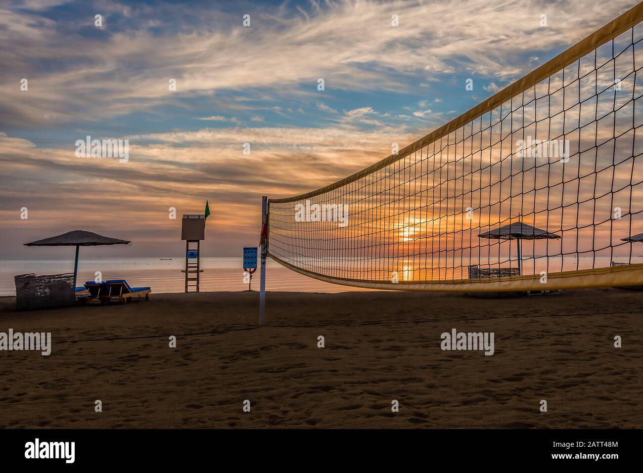 Volleyballnetz und Sonnenliegen an einem sandigen Strand bei Sonnenuntergang im Roten Meer, el Gouna, Ägypten, 16. Januar 2020 Stockfoto