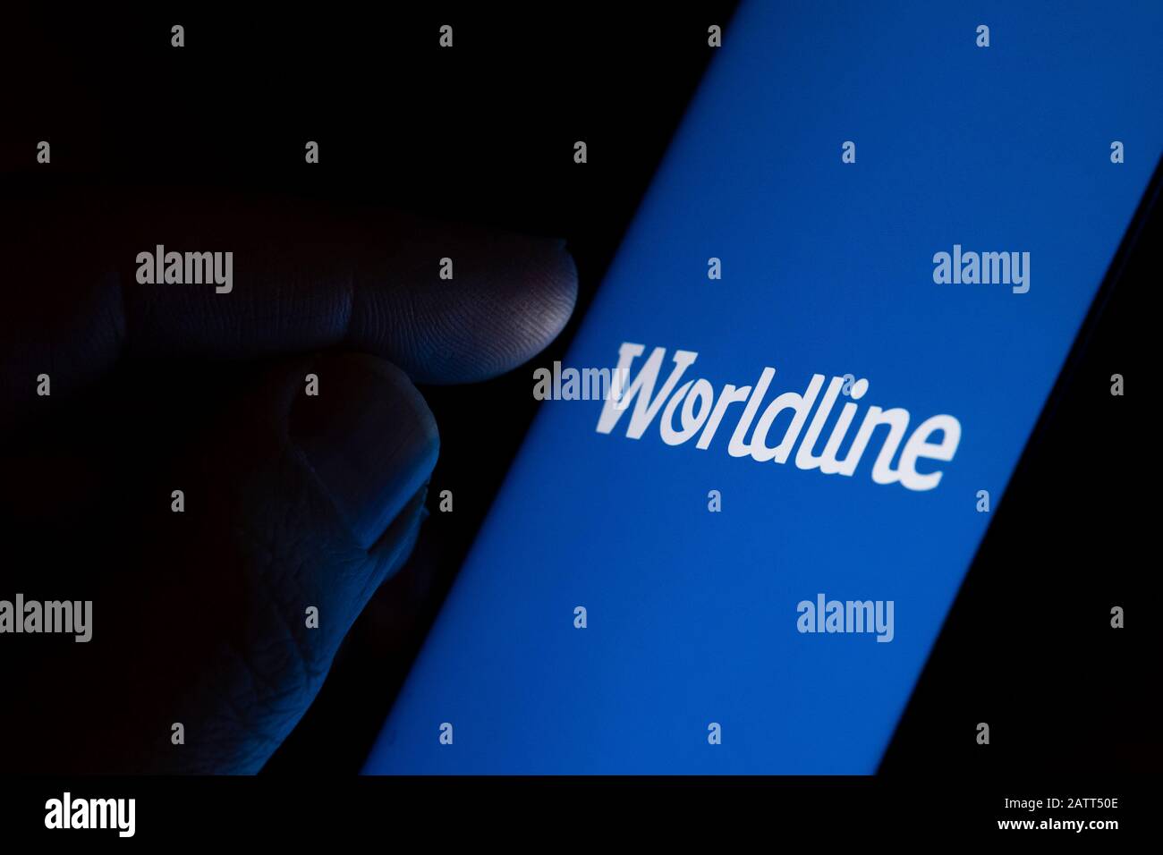 Logo der Firma Worldline Payment auf dem Bildschirm und Finger, um es zu berühren. Konzeptfoto. Stockfoto