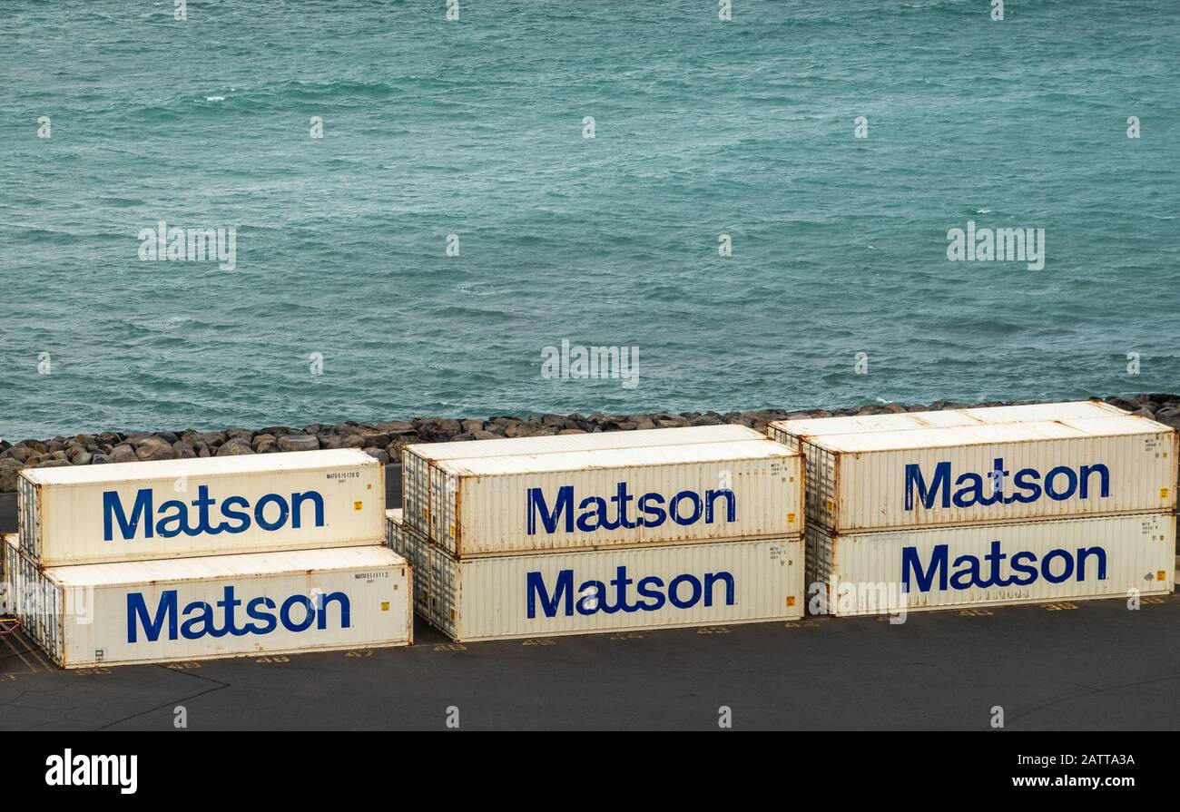Kahului, Maui, Hawaii, USA. - 13. Januar 2020: Ozeanhafen. Nahaufnahme der weißen Matson Transportbehälter, die auf einem Kai mit azurblauem Ozean als Kulisse gestapelt sind. Stockfoto