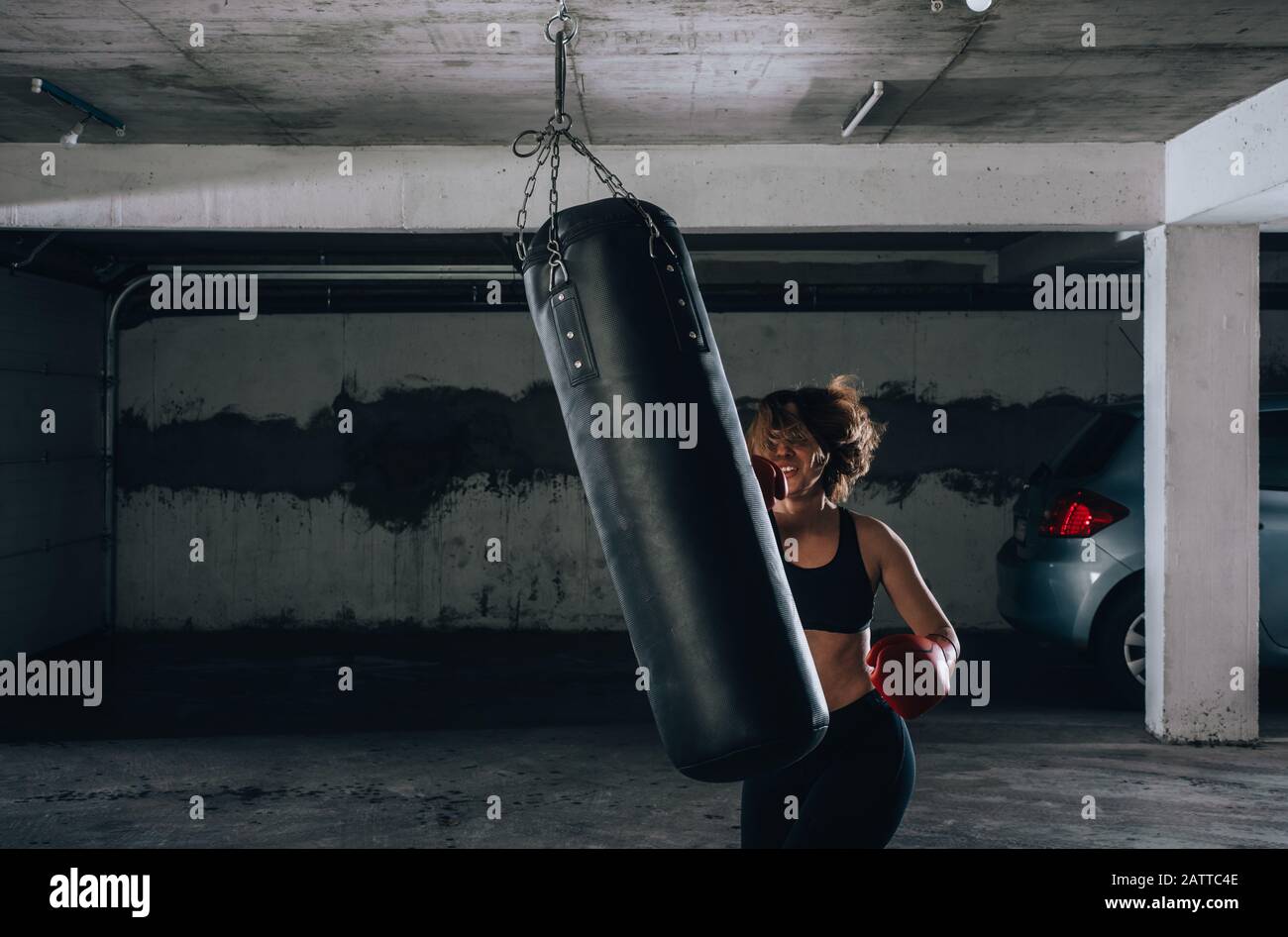 Starke junge Frau, die einen Boxsack in der Garage stanzt Stockfotografie -  Alamy